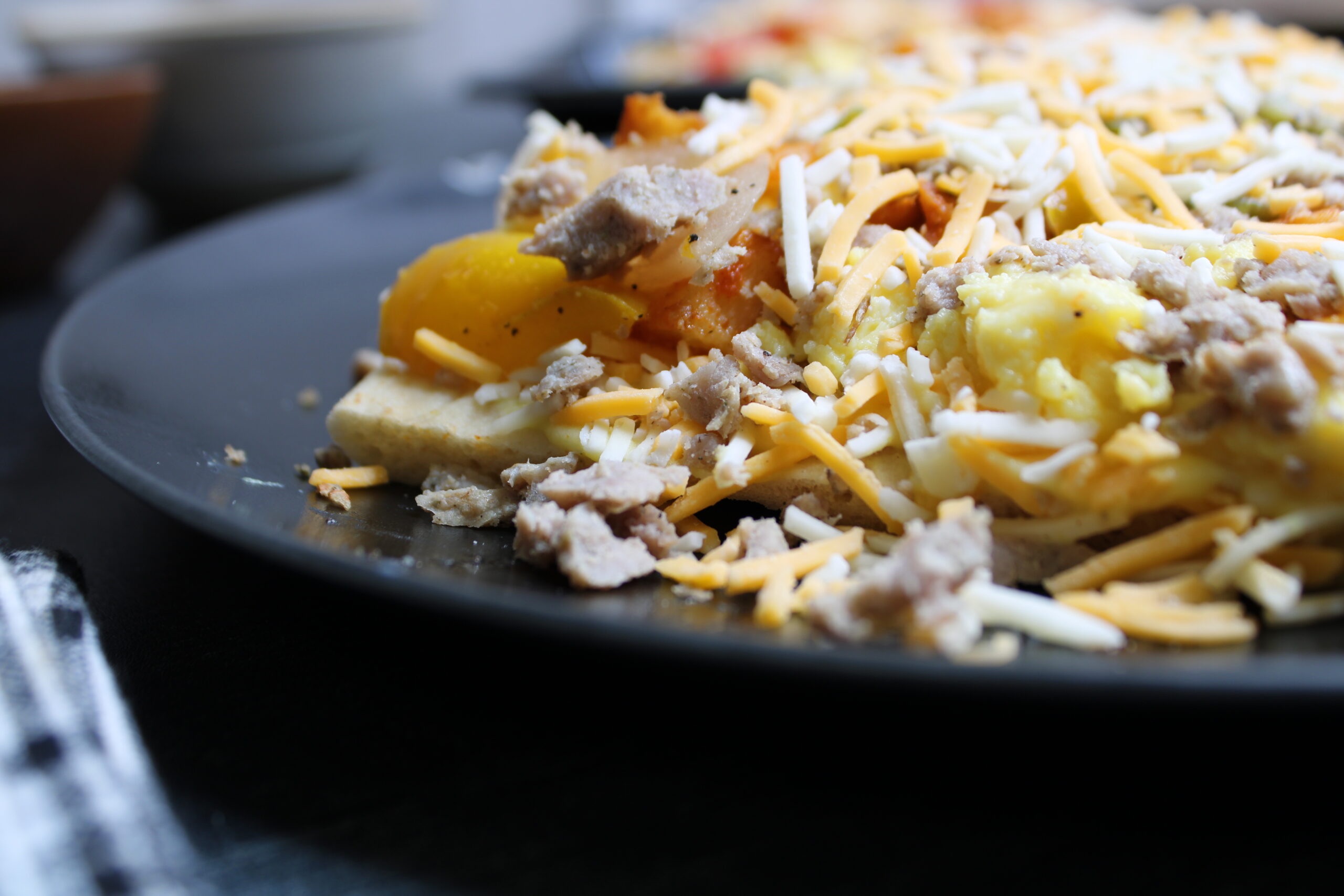 Chicken sausage breakfast flatbread with scrambled eggs, peppers, onions, and melted cheese